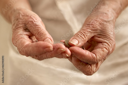 Photos Old woman's wrinkled hands counting small coins