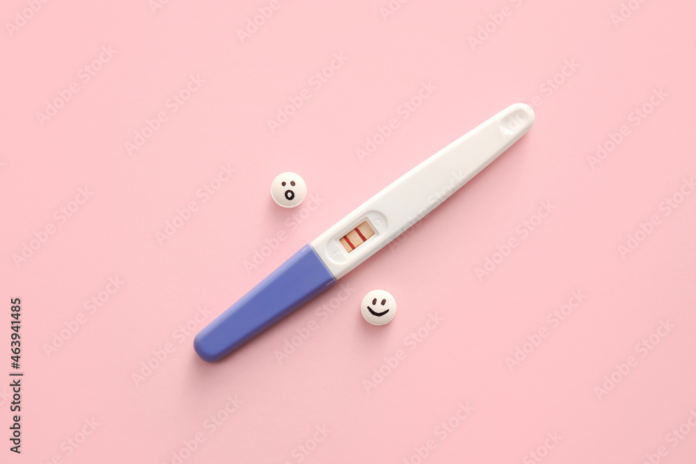Pregnancy test and pills with drawn faces on color background Pregnancy test and pills with drawn faces on color background