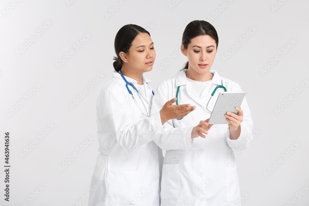 Portrait of female Asian doctors with tablet on light background Portrait of female Asian doctors with tablet on light background