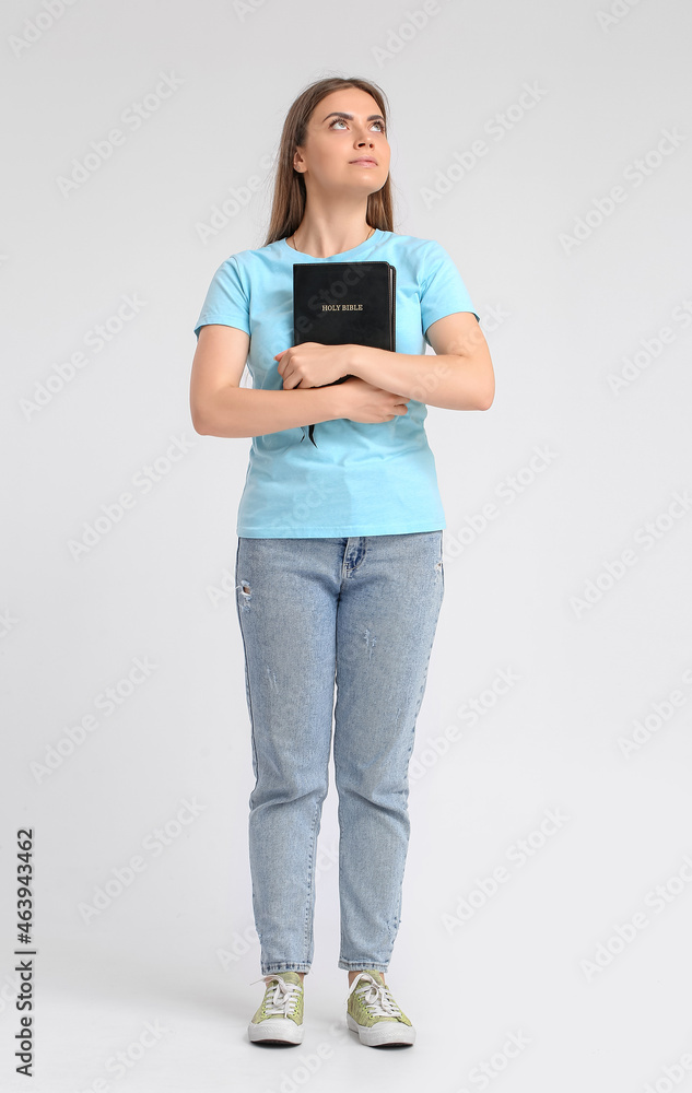 Young woman with Holy Bible on light background Young woman with Holy Bible on light background