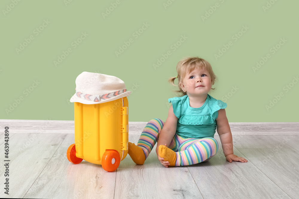 Cute baby girl with suitcase near color wall Cute baby girl with suitcase near color wall