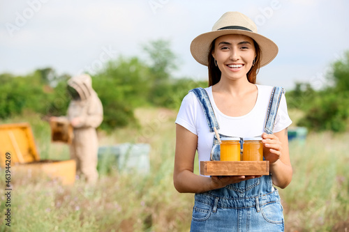 Female beekeeper with sweet honey at apiary