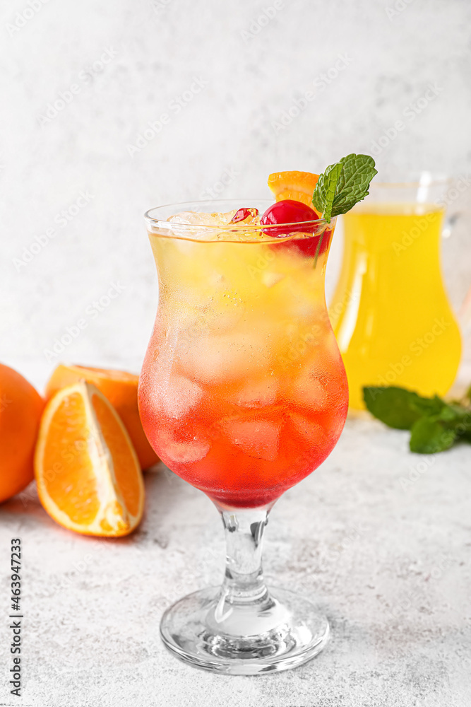 Fototapeta premium Glass of cold Tequila Sunrise cocktail on light background