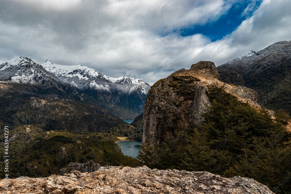 A small lake surrounded by mountains and forests A small lake surrounded by mountains and forests