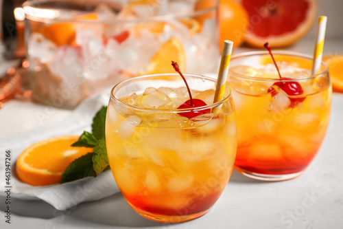 Glasses of cold Tequila Sunrise cocktail on light background