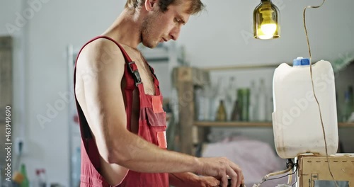 Handyman in overalls works with device part in workshop photo