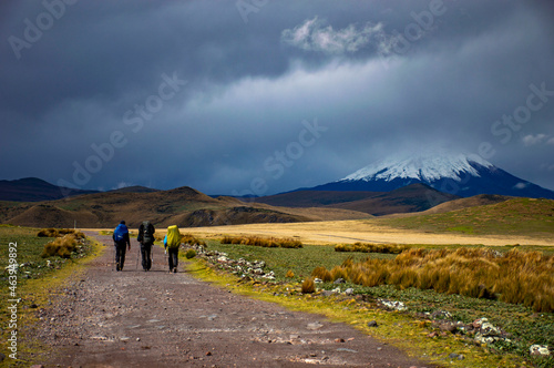 Hikers with backpacks walking under black clouds