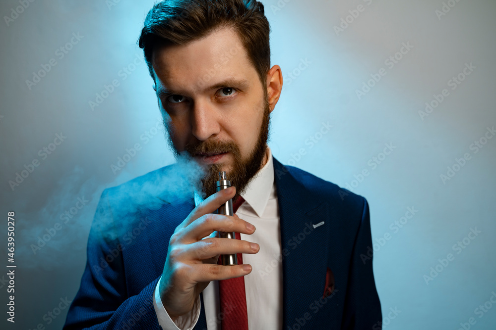 Man smoking e cigarette and looking at camera, smoke coming out his mouth   - obrazy, fototapety, plakaty 