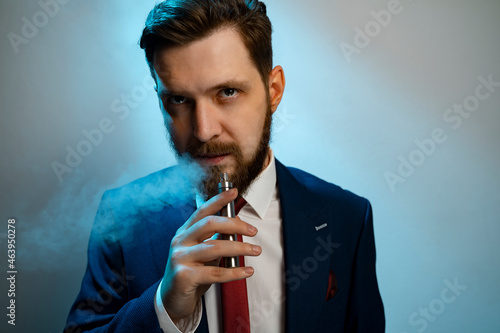 Man smoking e cigarette and looking at camera, smoke coming out his mouth 