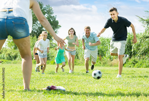 gambling family of six people happily playing in football together outdoors on summer sunny day