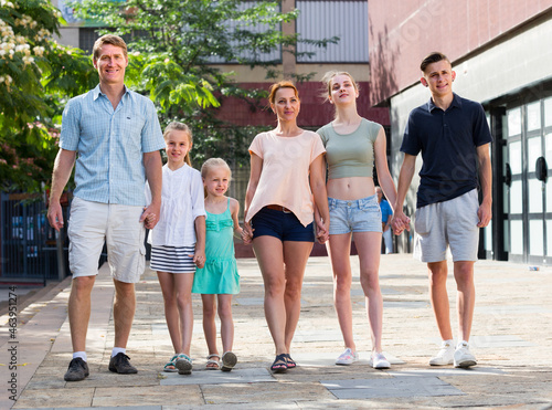 Fototapeta Naklejka Na Ścianę i Meble -  family of six people happily walking together in summer city