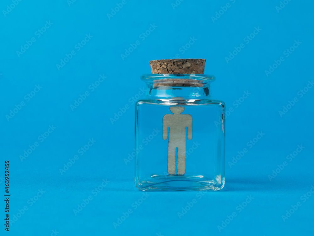 Wooden figure of a man in a glass flask on a blue background.