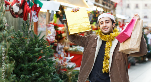 Happy young man delighted with purchases at Christmas market