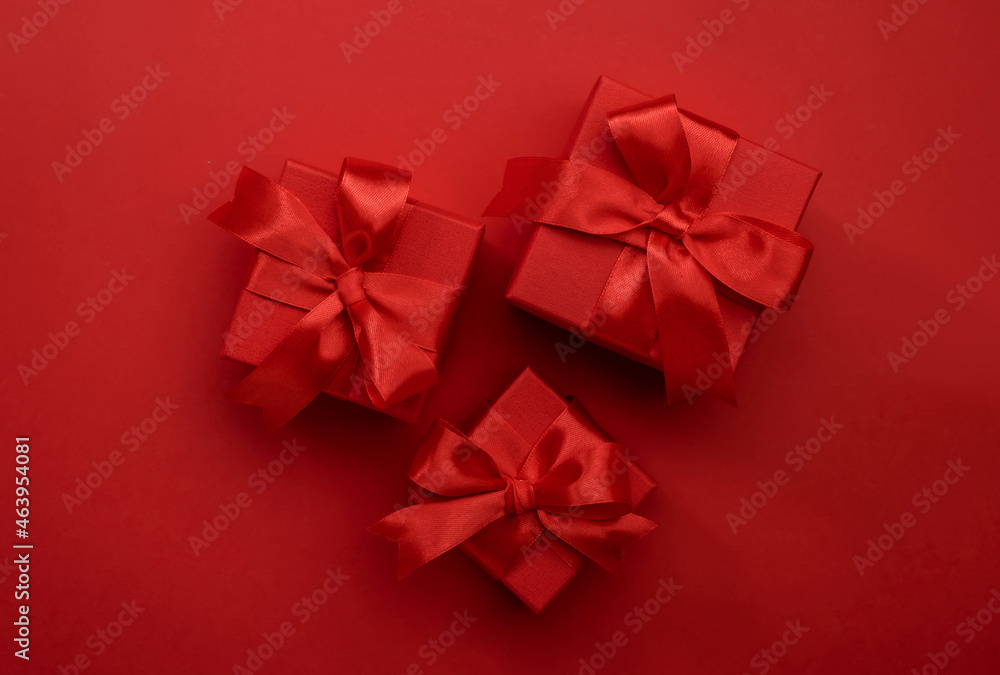 Red gift boxes with ribbons and bows on red background. Merry Christmas and Happy New Year template. Preparation for holidays. Top view. Copy space banner Red gift boxes with ribbons and bows on red background. Merry Christmas and Happy New Year template. Preparation for holidays. Top view. Copy space banner