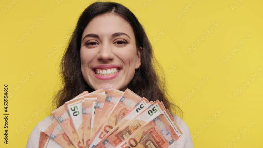 Close up portrait happy young woman holding cash euro in hands. Caucasian female 20s in casual light sweat shirt posing isolated on yellow background studio. People lifestyle concept. Close up portrait happy young woman holding cash euro in hands. Caucasian female 20s in casual light sweat shirt posing isolated on yellow background studio. People lifestyle concept.