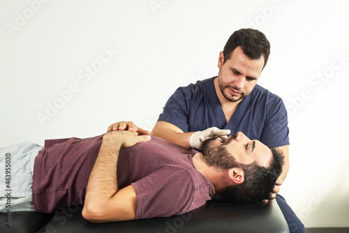 Physiotherapist performing a jaw examination on a patient