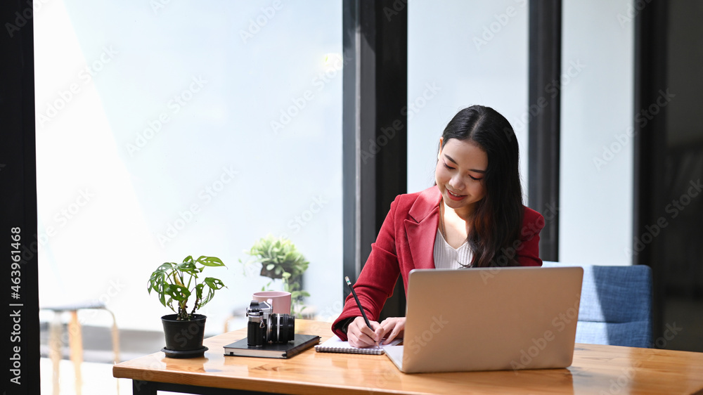 Young female entrepreneur sitting in modern workplace and working with laptop computer. Young female entrepreneur sitting in modern workplace and working with laptop computer.