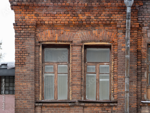 Two windows of the old mansion 19 century with brown bricks wall.