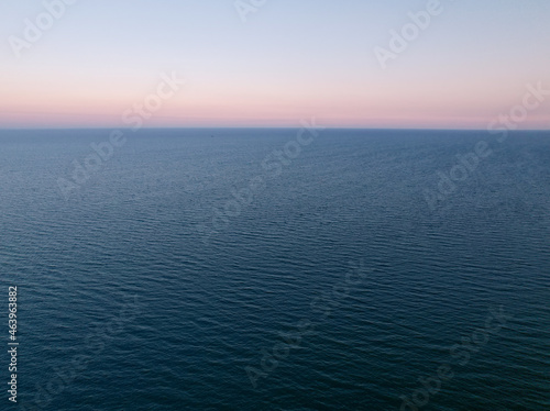Aerial view of the endless sea surface in calm windless weather on a late summer evening. © motodrinker_395