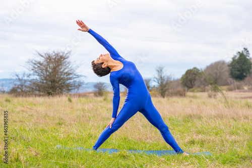 Athletic woman doing yoga in a grass field.