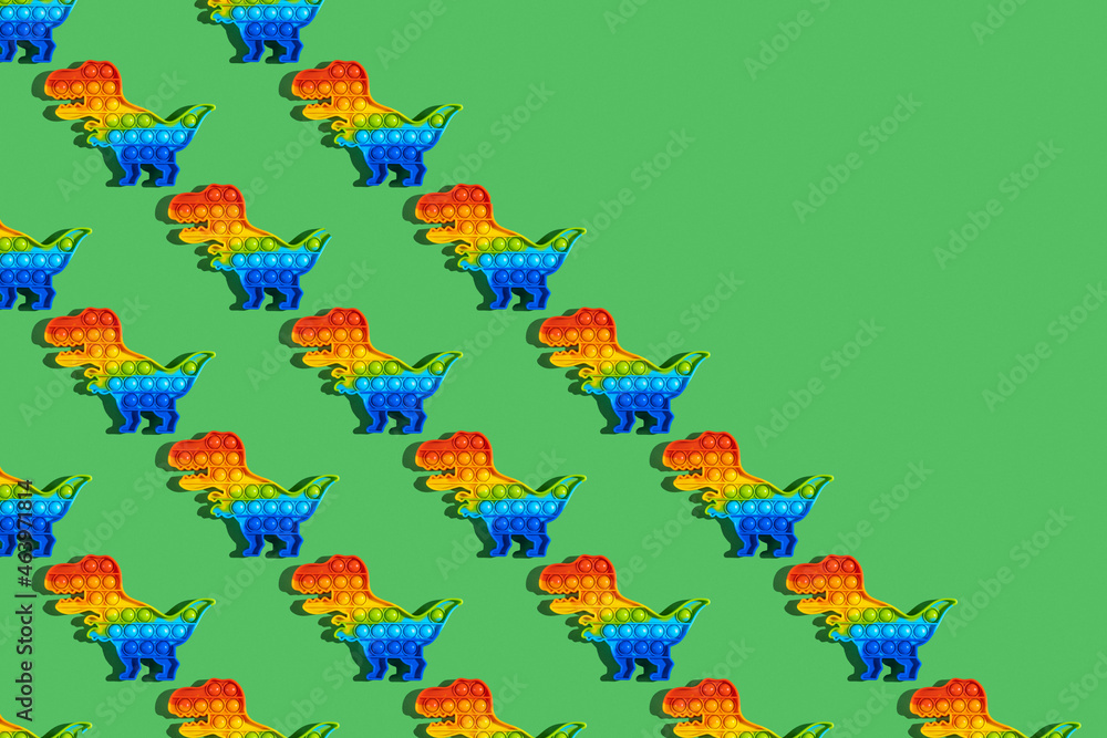 Obraz premium Seamless pattern with Sensory Fidget Toy in the form of dinosaur on green background. Pop It. Anti stress toy.