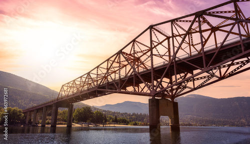 Big Orange Bridge over Kootenay River with Touristic Town in background. Sunrise Sky Art Render. Located in Nelson, British Columbia, Canada.