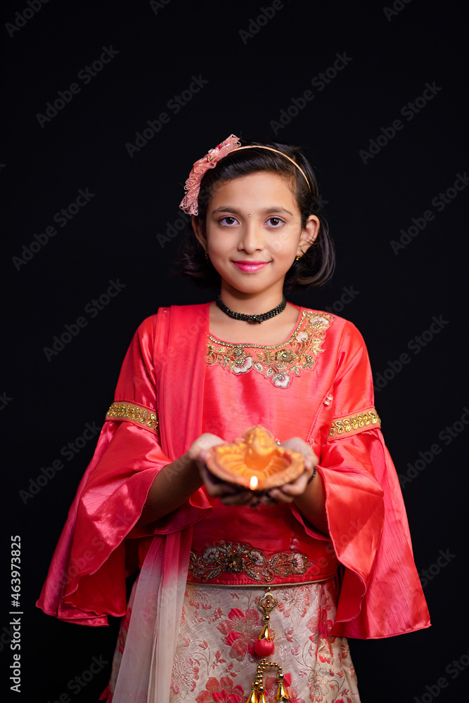 Cute Indian little girl holding diya or oil lamps for Diwali Celebration. Cute Indian little girl holding diya or oil lamps for Diwali Celebration.