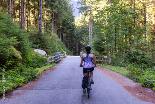 Wallpaper Mural Adventurous White Caucasian Woman on a bicycle riding on a path in Green Canadian Rain Forest. Seymour Valley Trailway in North Vancouver, British Columbia, Canada. Torontodigital.ca