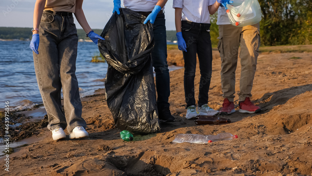 unrecognizable family collects plastic trash in bags near the coast.