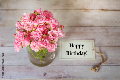Beautiful Pink Roses in  Vase and Happy Birthday card  on Wooden Background  
