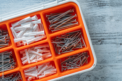 Box organizer for the screws and dowels on white wooden background, close up