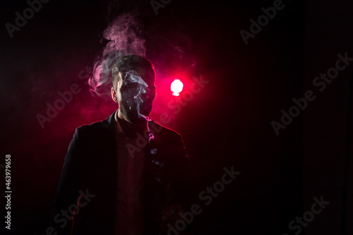 Photo of man with cigarette lighter on black background and pink light.