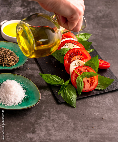 A hand placing fresh basil leaf to capresi salad. Copy space. photo