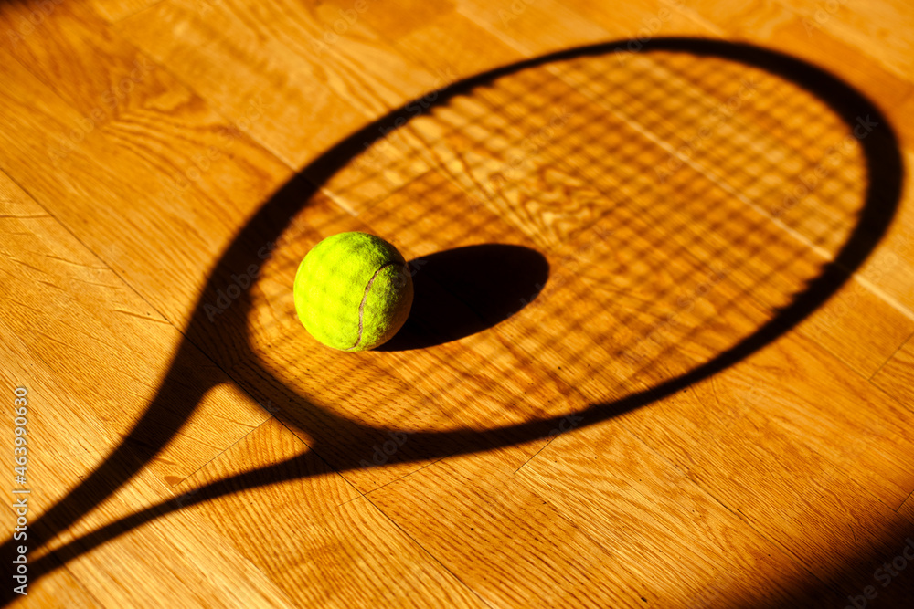 The sight of a tennis ball and the shadow on the floor from a tennis racket. Abstract background sports theme.