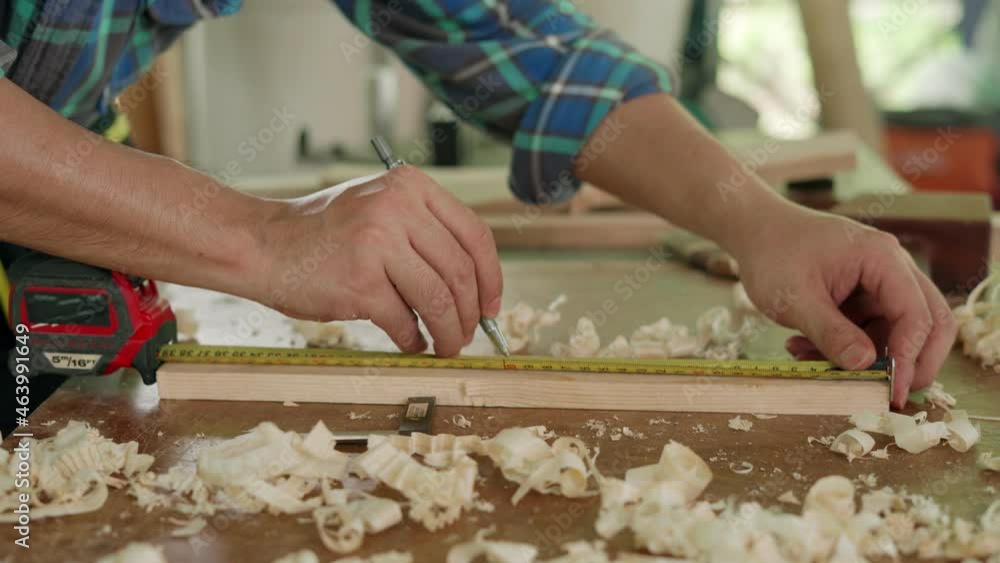 A carpenter measures wood planks to make furniture. small family industry. carpenter is adjusting the surface of the wood to the desired size. A carpenter measures wood planks to make furniture. small family industry. carpenter is adjusting the surface of the wood to the desired size.