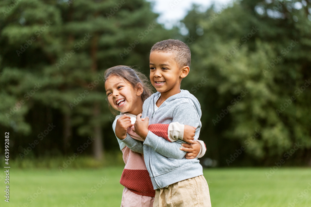 childhood, leisure and people concept - happy smiling little boy and girl hugging at park childhood, leisure and people concept - happy smiling little boy and girl hugging at park