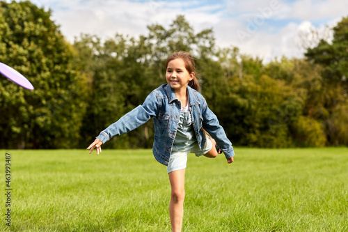 childhood, leisure and people concept - happy girl playing game with flying disc at park