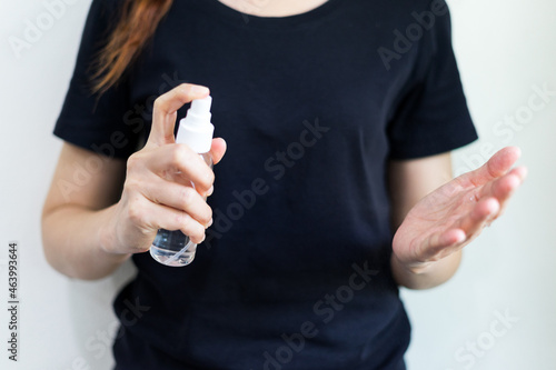 Cloes up woman in black t-shirt with alcohol based handwashing spray as a preventive hygiene measure against coronavirus infection. Antibacterial hand female sanitizer gel on white isolate background.