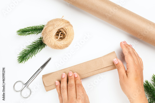 woman hands pack box with New Year gift in brown paper on white isolated background.  photo