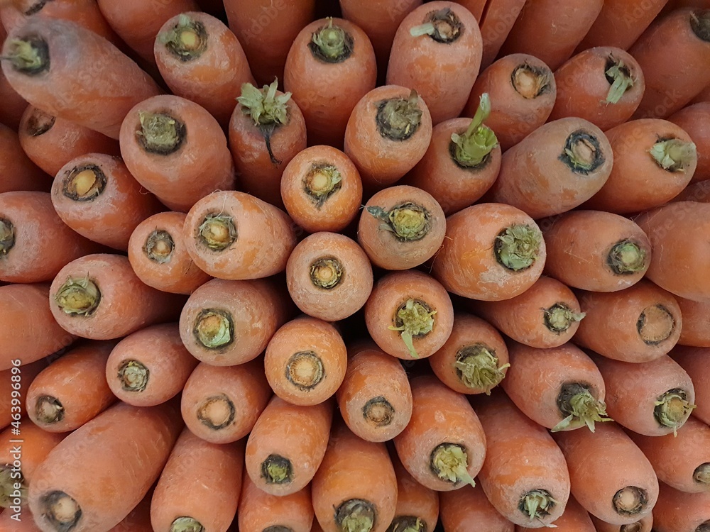 Lots of carrots, in a market. Carrots are a root vegetable rich in