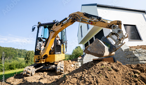 Mini excavator digging preparing ground under home garden photo