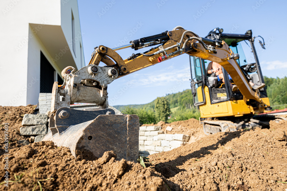 Fototapeta premium Mini excavator digging preparing ground under home garden