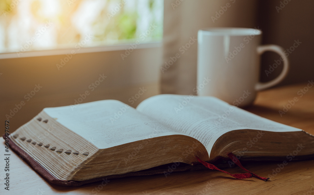 Open Bible and coffee in the morning on a wood table with nature backgound. Open Bible and coffee in the morning on a wood table with nature backgound.