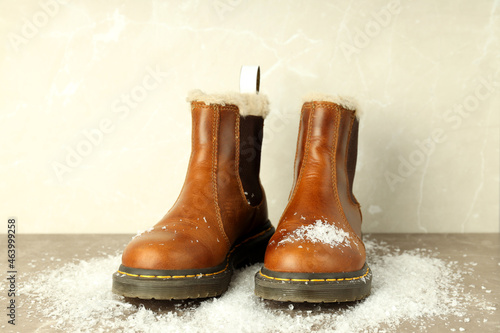 Boots with snow on gray textured table