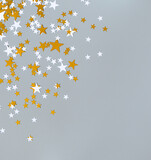 lots of confetti of white and golden stars on a gray background