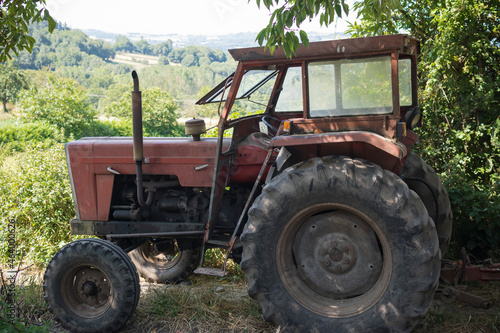 Viejo tractor rojo abandonado o aparcado en mitad del campo