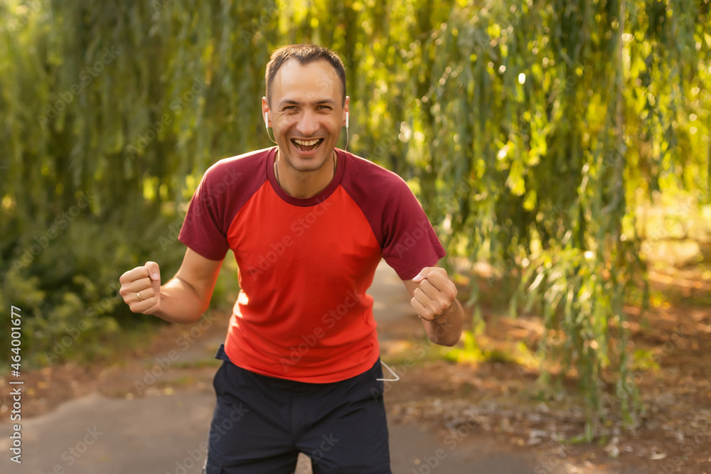 Successful man raising arms after cross track running on summer