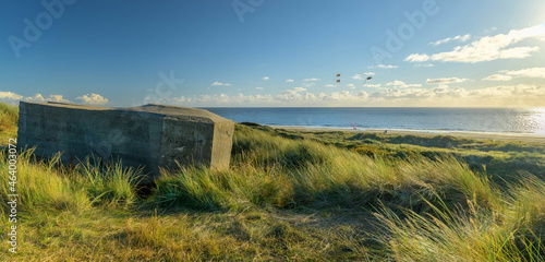 Bunker near Blåvand on wide dune of Blåvandshuk with beach view and people playing in the background situated  on the west coast of Jutland by Esbjerg, Denmark.Second World War bunker of Atlantic Wall photo