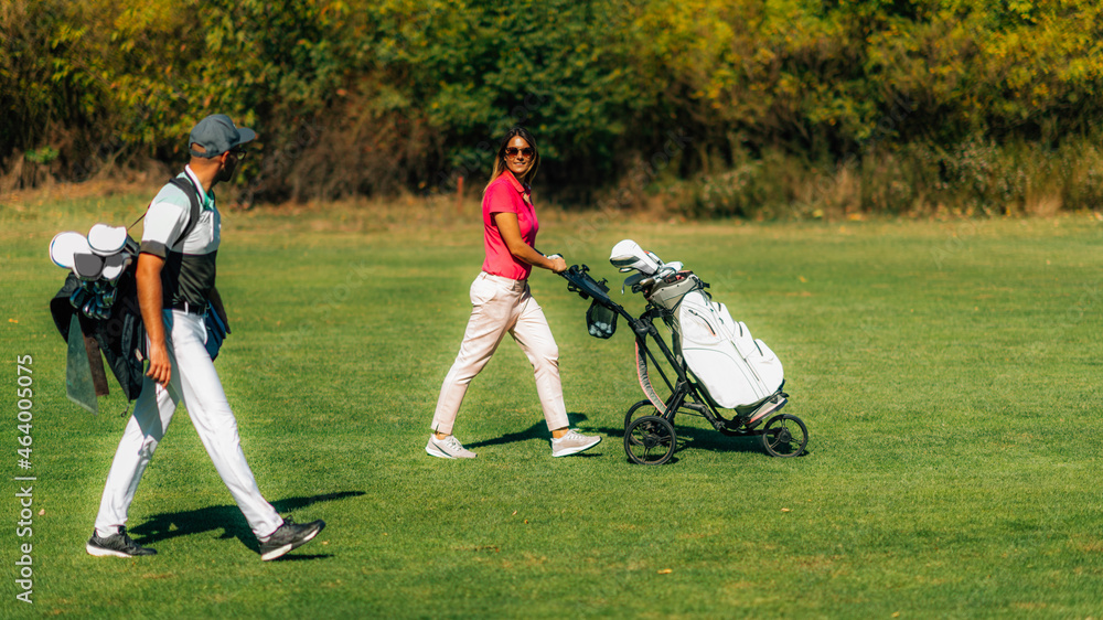 Golfing lifestyle couple walking on the golf course, enjoying a beautiful autumn day Golfing lifestyle couple walking on the golf course, enjoying a beautiful autumn day