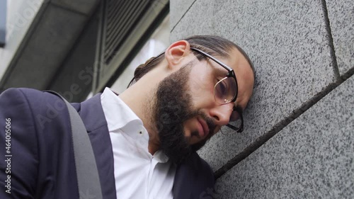 Depressed brunette man leaning on wall, getting bad news, lost of beloved person